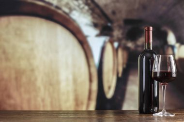 Şarap şişesi ve gözlüklü şarap mahzeni. Şarap mahzeninde kırmızı şarap tatma. Metin için boşluk ile.