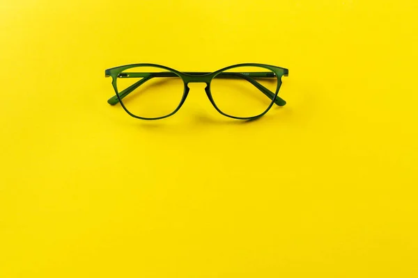 Stylish eyeglasses over yellow background. Optical store, glasses selection, eye test, vision examination at optician, fashion accessories concept. Space for text.