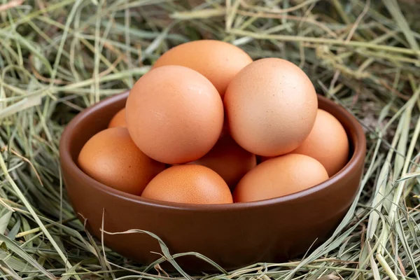 Gray chicken eggs in a clay bowl on a background of hay. Farm concept.