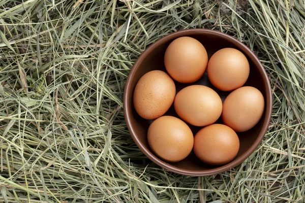 Gray chicken eggs in a clay bowl on a background of hay. Farm concept.