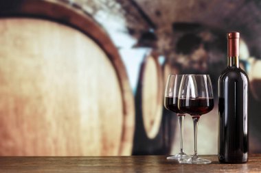 Şarap şişesi ve gözlüklü şarap mahzeni. Şarap mahzeninde kırmızı şarap tatma. Metin için boşluk ile.