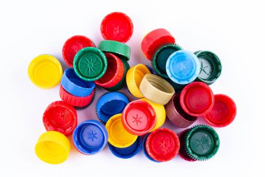 Beyaz arka planda plastik şişe kapakları. Kapak malzemesi geri dönüştürülebilir. Geri dönüşüm toplama ve plastik şişe kapaklarını işleme. Plastik şişelerin kapaklarını geri dönüşümden önce çıkar.