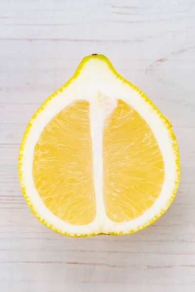 Half of a lemon on a white wooden background. creative food concept. Tropical organic fruit, citrus, vitamin C. Lemon slices.