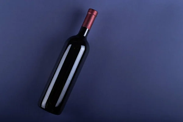 Bottle of red wine without a label on a purple paper background. Mockup drink with place for you label and text. Space for text.Top view.