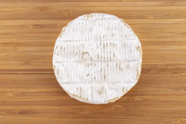 Brie type of cheese. Camembert cheese. Fresh Brie cheese. French cheese on a wooden table.