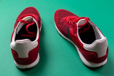 Pair of red sport shoes on green background. Space for text.
