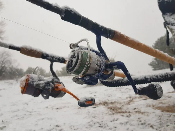 Fishing on the feeder, in the river. Fishing rod and reel close-up. The fishing tackle was covered with snow.