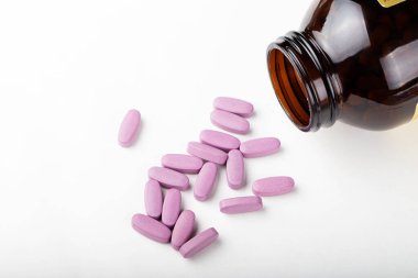 İlaç şişesinden dökülen pembe ilaç ve haplar. Antidepresan ilaçlar. Metin için boşluk.