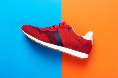 Renkli bir arka planda bir çift spor ayakkabısı. Çok renkli arka planda yeni spor ayakkabılar, kopyalama alanı. Sıradan moda spor ayakkabıları kırmızı renkler. Biçim konsepti.