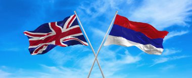 Büyük Britanya ve Cumhuriyet Cumhuriyeti 'nin bayrakları güneşli bir günde gökyüzüne karşı bayrak direkleri üzerinde rüzgarda sallanıyor. İki ülke arasındaki ilişkiyi, diyaloğu sembolize ediyor. 3d illüstrasyon,