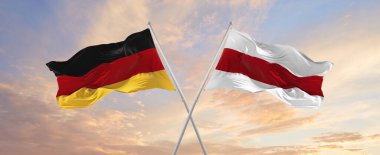 Almanya ve Belarus 'un bayrakları rüzgarda dalgalanırken bayrak direkleri gökyüzüne karşı güneşli bir günde bulutlarla. İki ülke arasındaki ilişkiyi, diyaloğu sembolize ediyor. 3d illüstrasyon,