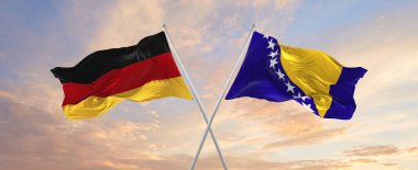 Almanya ve Bosna-Hersek 'in bayrakları rüzgarda dalgalanırken güneşli bir günde gökyüzüne doğru bayrak direkleri sallıyor. İki ülke arasındaki ilişkiyi, diyaloğu sembolize ediyor. 3d illüstrasyon,