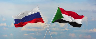 Rusya ve Sudan 'ın bayrak direkleri rüzgarda dalgalanırken güneşli bir günde gökyüzüne karşı bulutlar. İki ülke arasındaki ilişkiyi, diyaloğu sembolize ediyor. 3d illüstrasyon,