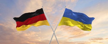 Almanya ve Ukrayna 'nın bayrakları rüzgarda dalgalanırken bayrak direkleri gökyüzüne karşı güneşli bir günde bulutlarla. İki ülke arasındaki ilişkiyi, diyaloğu sembolize ediyor. 3d illüstrasyon,