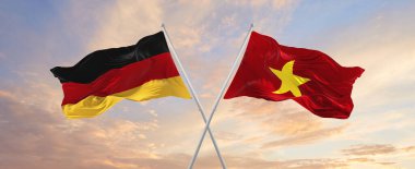 Almanya ve Vietnam 'ın bayrakları rüzgarda dalgalanırken bayrak direkleri gökyüzüne karşı güneşli bir günde bulutlarla. İki ülke arasındaki ilişkiyi, diyaloğu sembolize ediyor. 3d illüstrasyon,