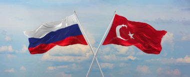 Rusya ve Türkiye 'nin bayrak direkleri rüzgarda dalgalanırken güneşli bir günde gökyüzüne karşı bulutlar. İki ülke arasındaki ilişkiyi, diyaloğu sembolize ediyor. 3d illüstrasyon,