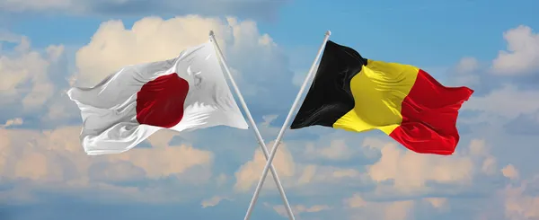 在阳光明媚的日子 日本和比利时的国旗在风中飘扬 旗杆迎着天空飘扬 象征两国关系 两国间的对话 3D说明 — 图库照片