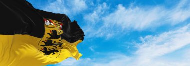 Baden-Wurttemberg eyaletinin bayrağı, bulutlu arka planda daha büyük kollar günbatımında, panoramik manzara. Almanya Federal Cumhuriyeti. Geniş afiş afiş için boşluk kopyala. 3d illüstrasyon