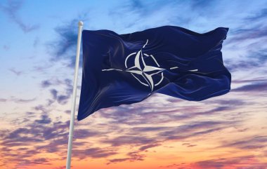 Minsk, Belarus - Mayıs 2021: NATO bayrağı güneşli bir günde gökyüzüne doğru bayrak direği sallıyor.