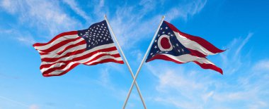 ABD ve Ohio 'nun iki bayrağı güneşli bir günde gökyüzüne doğru bayrak direkleri sallıyor. 3d illüstrasyon