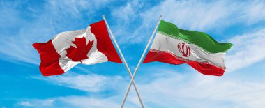 Kanada ve İran 'ın ulusal bayraklarını aştı bulutlu gökyüzünde rüzgarda dalgalanan bayrak. İlişkiyi, diyaloğu, iki ülke arasında seyahat etmeyi sembolize ediyor. Boşluğu kopyala
