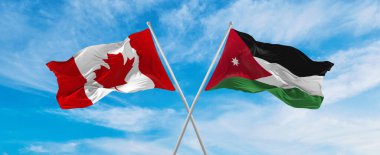 Kanada ve Ürdün bayraklarını aştı bulutlu gökyüzünde rüzgarda dalgalanan bayrak. İlişkiyi, diyaloğu, iki ülke arasında seyahat etmeyi sembolize ediyor. Boşluğu kopyala