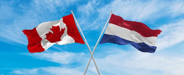 カナダの国旗とオランダの国旗が雲の多い空で風になびいていました 両国間の旅行を象徴する スペースのコピー — ストック写真