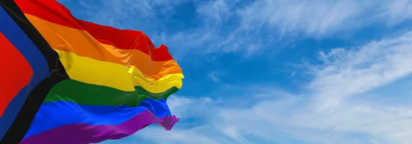 Social Justice Pride flag waving in the wind at cloudy sky. Freedom and love concept. Pride month. activism, community and freedom Concept. Copy space. 3d illustration.