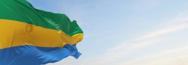 Gabon 'un resmi bayrağı bulutlu arka planda, günbatımında, panoramik manzarada. Vatansever ve seyahat kavramı. Geniş afiş afiş için boşluk kopyala. 3d illüstrasyon