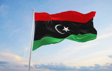 Libya 'nın resmi bayrağı bulutlu arka planda, günbatımında, panoramik manzaralı. Vatansever ve seyahat kavramı. Geniş afiş afiş için boşluk kopyala 