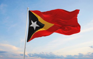 Günbatımında bulutlu arka planda Timor Leste 'nin resmi bayrağı, panoramik manzara. Vatansever ve seyahat kavramı. Geniş afiş afiş için boşluk kopyala 