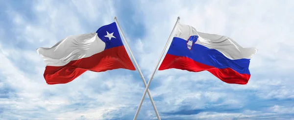 구름낀 하늘에서 국기와 슬로베니아 국기가 바람에 흔들리고 있었다 관계를 상징하고 — 스톡 사진