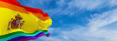 LGBT İspanya bayrağı bulutlu gökyüzünde rüzgarda dalgalanıyor. Özgürlük ve aşk kavramı. Gurur ayı. Eylemcilik, toplum ve özgürlük kavramı. Uzayı kopyala 3d illüstrasyon.