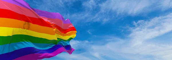 nine-stripe pride flag waving in the wind at cloudy sky. Freedom and love concept. Pride month. activism, community and freedom Concept. Copy space. 3d illustration.