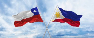Şili ve Filipinler 'in ulusal bayraklarını aştı bulutlu gökyüzünde rüzgarda dalgalanan bayrak. İlişkiyi, diyaloğu, iki ülke arasında seyahat etmeyi sembolize ediyor. Boşluğu kopyala