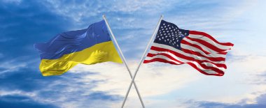 Amerika Birleşik Devletleri ve Ukrayna 'nın bulutlu gökyüzünde rüzgarda dalgalanan iki çapraz bayrak. İlişki kavramı, diyalog, iki ülke arasında seyahat. 3d illüstrasyon