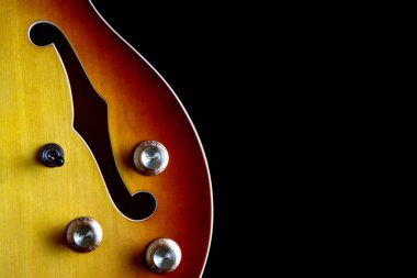 Yarı akustik elektro gitar gövdesinin kısmi görünümü siyah bir arkaplanda izole edilmiş