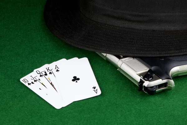 在被毛毡盖住的游戏桌上玩带有手枪和帽子的纸牌 — 图库照片