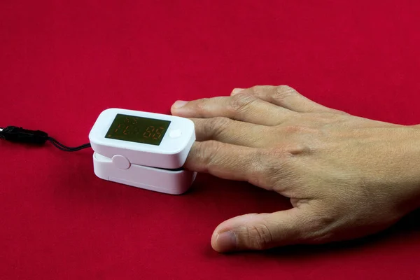 Medidor Nivel Oxígeno Médico Con Dedo Insertado Una Superficie Roja — Foto de Stock