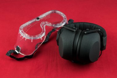 Kırmızı arka planda izole edilmiş işitme ve güvenlik gözlükleri