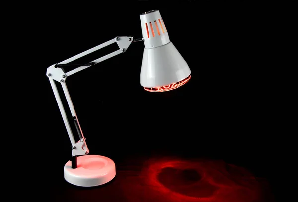 Illuminated infra red health lamp isolated on a black background