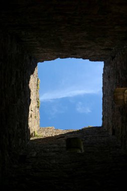 Eski bir kale duvarının penceresinden mavi gökyüzü manzarası