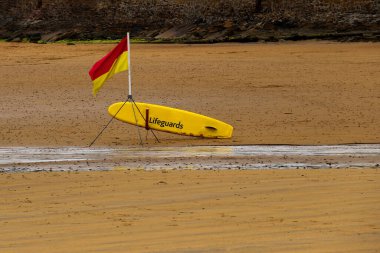 Lifeguard position flag and paddle board at a coastal beach