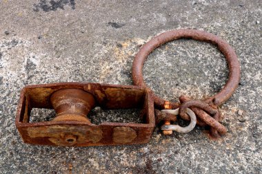 Old rusting steel winch pulley and ring at a coastal harbour location