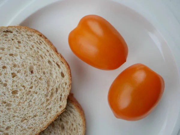 Yuvarlak beyaz bir tabakta sarı domatesler, düz uzanmış. Modern görüntü, sebze manzarası.