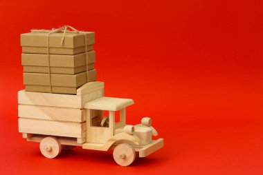 Kırmızı arka planda kutuları olan tahta oyuncak kamyon.