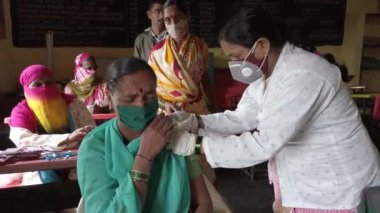 KOLHAPUR-INDIA - 31 Temmuz 2021: Bir tıp çalışanı Kolhapur 'daki köyde Covid-19 Coronavirus aşısı ile bir kadını aşıladı.