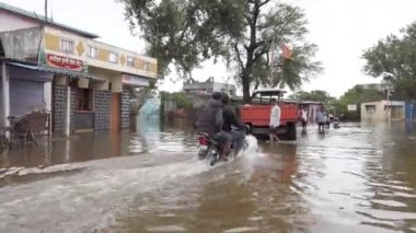 KOLHAPUR-INDIA - 29 Temmuz 2021: Bir adam, batı Maharashtra 'da şiddetli muson yağmurları sonrasında Kolhapur' un Herwad köyündeki sel basmış bir caddede scooter sürüyor.