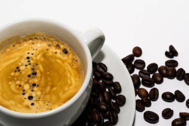 Hollanda, Ocak 2022 'de. Bir fincan kahve, beyaz arka planda kahve çekirdekleri..