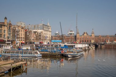 Amsterdam, Hollanda, Nisan 2022. Damrak 'ta kanal botları ve Amsterdam' daki merkez istasyonu var. Yüksek kalite fotoğraf